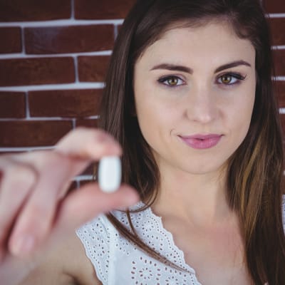 Frau zeigt weiße Pille