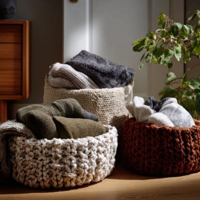 Warme Pullover und Decken quellen aus grob gestrickten Körben hervor und schaffen eine gemütliche und einladende Atmosphäre in einem stilvollen Zuhause