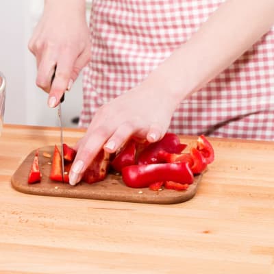 Rote Paprika auf einem Schneidebrett schneiden