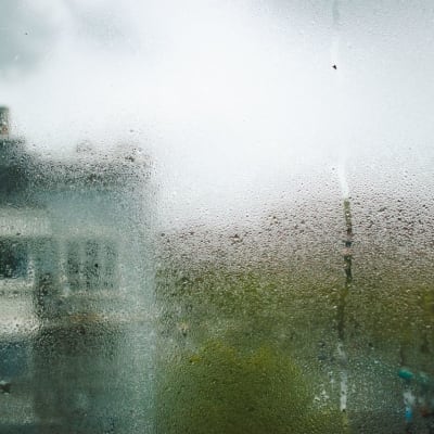 Blick auf die Gebäude von Shanghai durch ein taufeuchtes Fenster an einem bewölkten Tag.