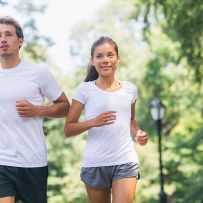 Läufer, die gemeinsam im Stadtpark trainieren und in weißen T-Shirts für einen guten Zweck laufen. Sport und Fitness: Freunde, die gemeinsam im Freien laufen. 