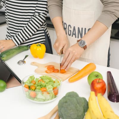 Kochen in der Familienküche. Ein junges Paar kocht und hilft sich gegenseitig bei der Zubereitung des Abendessens mit Gemüse.