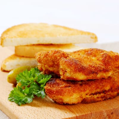 Goldbraun gebratene vegane Schnitzel mit frischer Petersilie und knusprigen Toastscheiben.