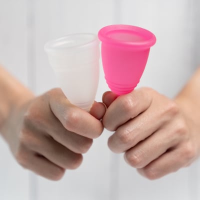 Nahaufnahme einer Frauenhand, die eine Menstruationstasse hält.