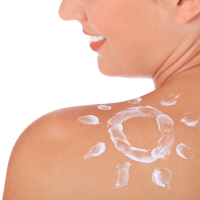 Schulter einer attraktiven jungen Frau mit Sonnencreme auf weißem Hintergrund. Alles auf weißem Hintergrund.