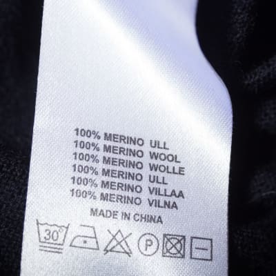 100-Merinowolle-Etikett auf dem dunkelblauen Wollstoff des Pullovers.