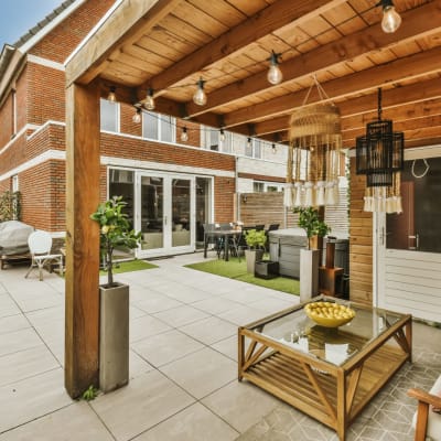 ein Außenwohnbereich mit Terrassenmöbeln und Topfpflanzen an der Seite des Hauses, umgeben von Backsteinmauern