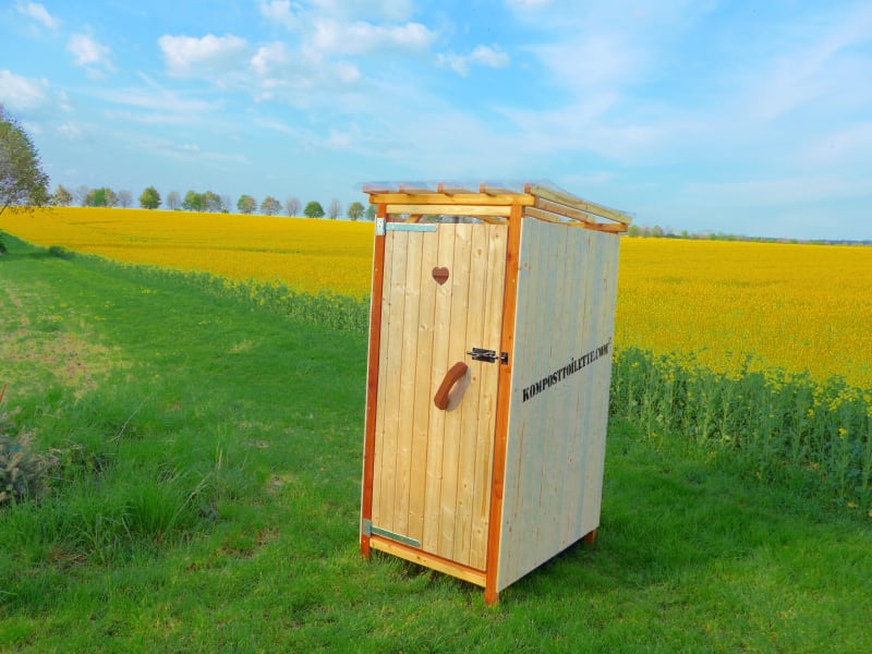 Toilettenhäuschen auf Wiese mit Rapsfeld | © komposttoilette.com