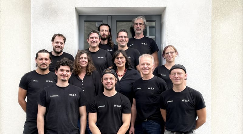 Das Team von W&A Wohnen / Tischlerei in schwarzen W&A-Shirts vor dem Betrieb in Langenfeld | © W&A Wohnen / Tischlerei