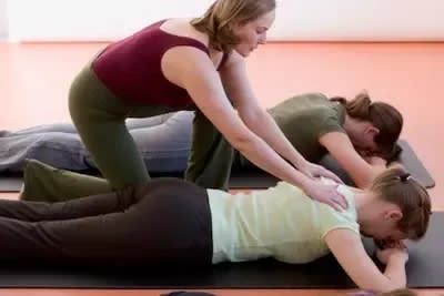 Hilfestellung bei einer Dehnung in Bauchlage | © Pilates Studio Hamburg / Sabine Büttner Photography