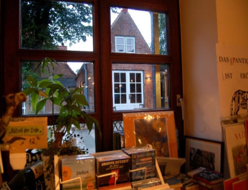 Antiquariatsbereich im Peter Panter Buchladen mit gerahmten Bildern und Blick in den Innenhof | © Peter Panter Buchladen