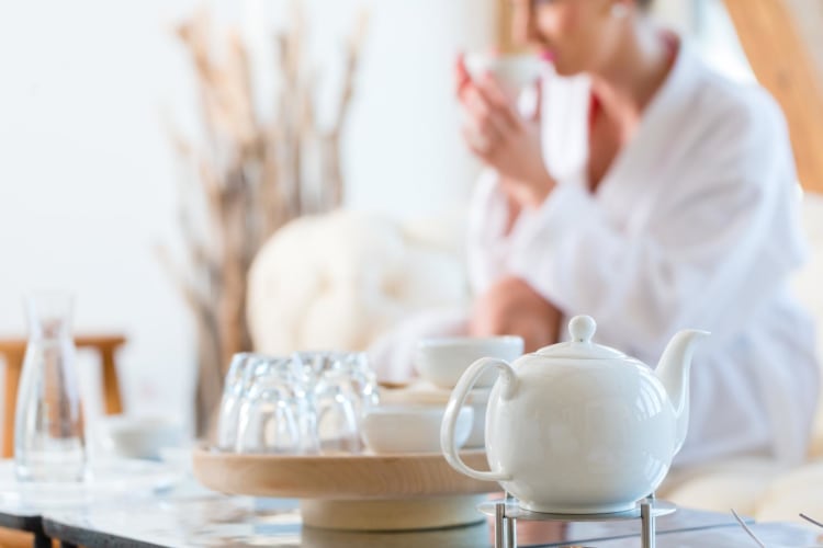 Frau im Bademantel, die im Ruheraum eines Ayurveda Wellness-Spas Tee trinkt