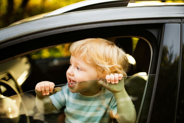 Kleiner blonder Junge schaut lustig aus einem Autofenster null