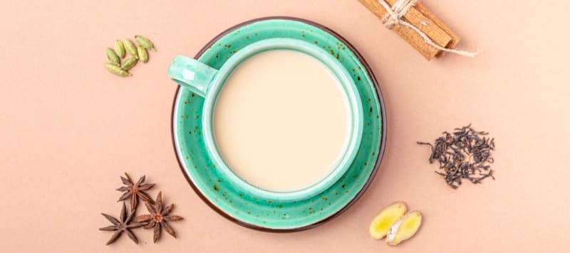 Gesundes indisches Getränk Masala Chai – heißes Teegetränk mit Milch und Gewürzen in rustikaler grüner Teetasse  null