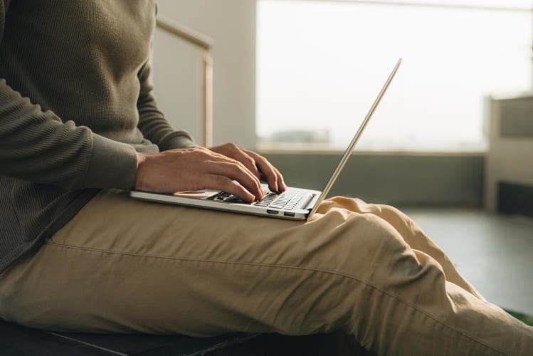 ein Geschäftsmann, der mit dem Laptop auf den Knien sitzt.