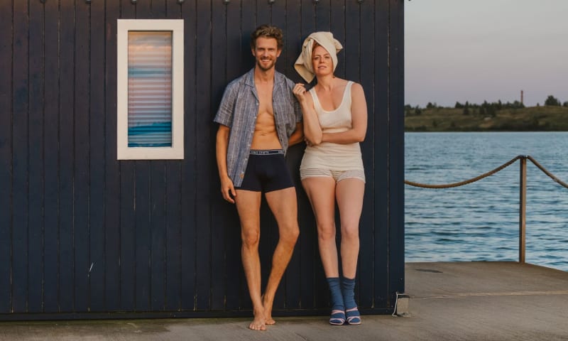 Frau und Mann in natürlicher Bio-Unterwäsche aus Bio-Baumwolle vor einer Badehütte am See. Natürliche Bio-Baumwoll-Unterwäsche für Damen und Herren – weich, hautfreundlich und zeitlos. LIVING CRAFTS