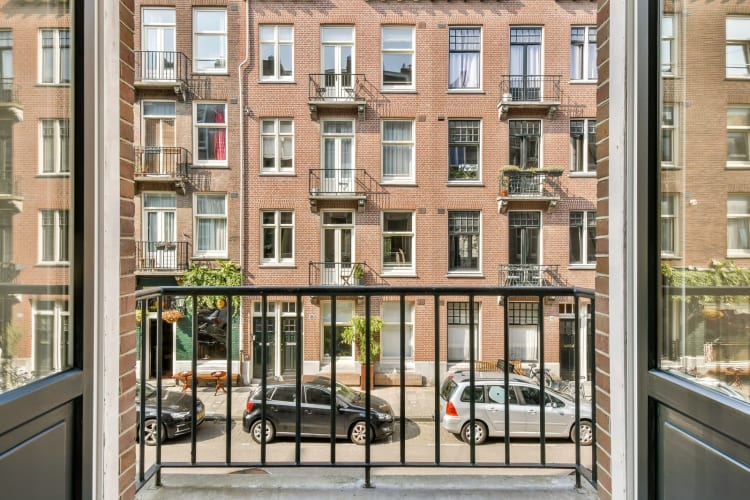  Ein ruhiger Blick von einem Balkon, eingerahmt von modernen Geländern, der die städtische Architektur und die darunter geparkten Autos offenbart. null