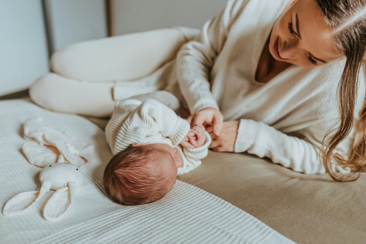 Eine Frau mit einem Baby liegend auf dem Bett null