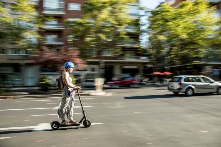 Junge Frau fährt auf E-Scooter durch die Stadt JavyGo auf Unsplash