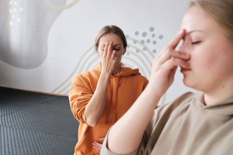 Zwei Frauen machen Breathwork und halten ihre Hand an die Nase für eine bewusste Atmung null