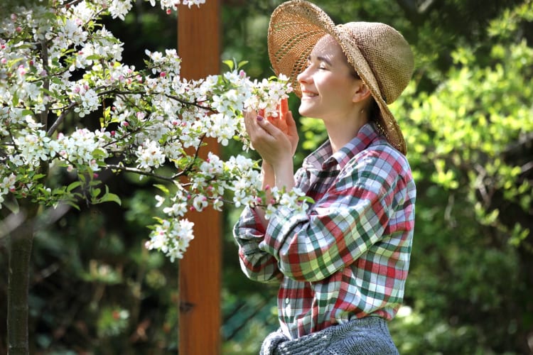 Eine glückliche Frau lächelt inmitten von Apfelblüten