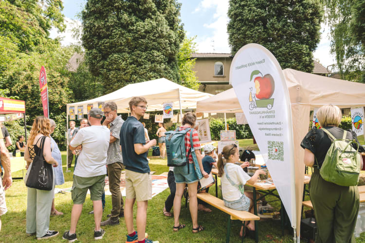 Besucher*innen am Stand des Ernährungsrats Essen auf dem Gutes Klima Festival, Kinder experimentieren an einer Bierbank, Pavillons auf der Wiese. © André Symann