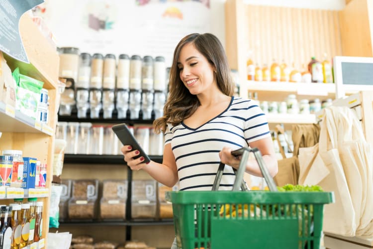 Junge Frau mit Handy in einem Naturkostladen null