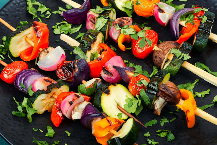 Veganes Schaschlik aus frischem Gemüse am Spieß auf einem rustikalen Holztisch. null