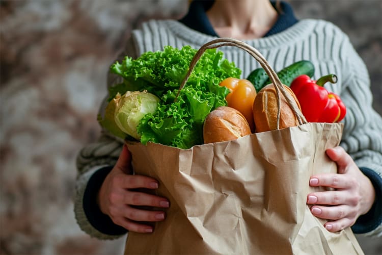 Junge Frau hält Papiertüte aus Supermarkt mit Lebensmitteln null