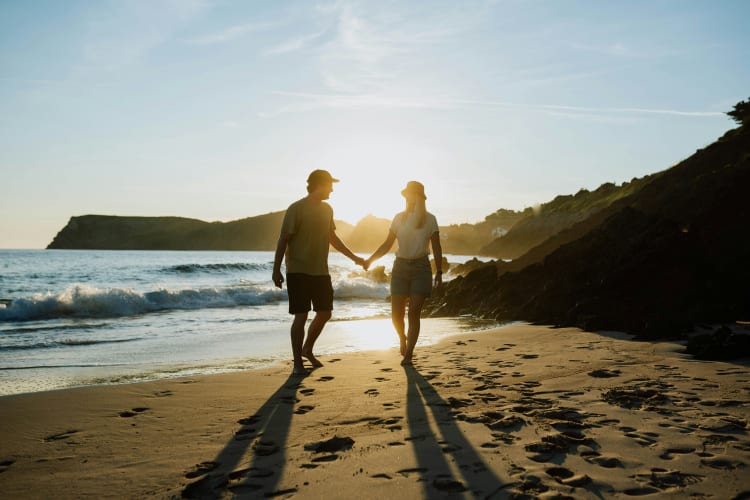 Ein Mann und eine Frau gehen händchenhaltend am Strand spazieren null