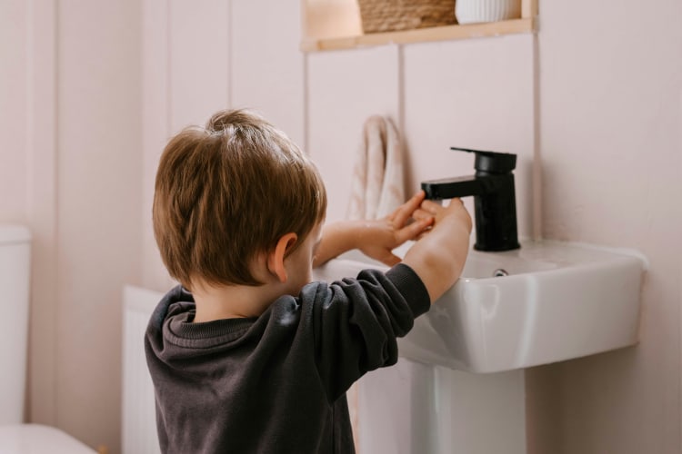 Junge wäscht sich am Waschbecken die Hände