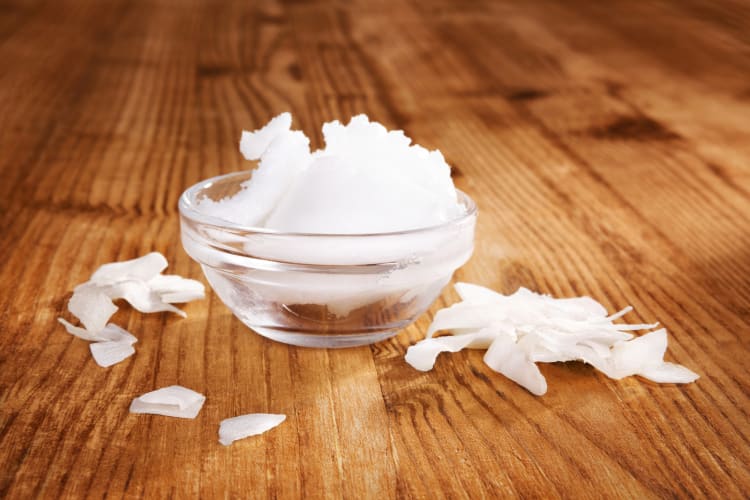 Festes Bio-Kokosöl in einer Schüssel mit Kokosflocken vor einem hölzernen Hintergrund. Gesunde vegane Ernährung und Kochen. null