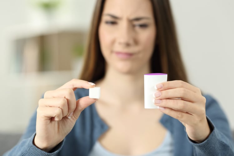 Verwirrte Frau zweifelt zu Hause an der Unterscheidung zwischen Saccharin und Zucker.