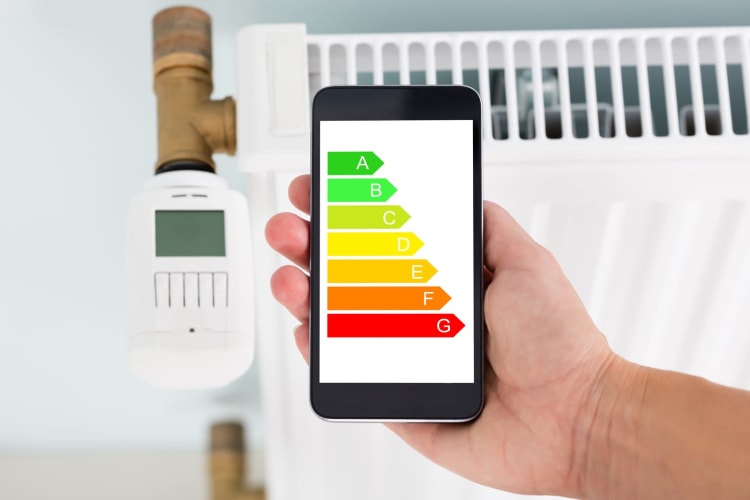 Die Person reguliert die Temperatur eines digitalen Smart-Thermostats per Handy-App zu Hause.