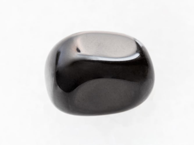 polierter schwarzer Onyx-Edelstein auf weißem Marmoruntergrund