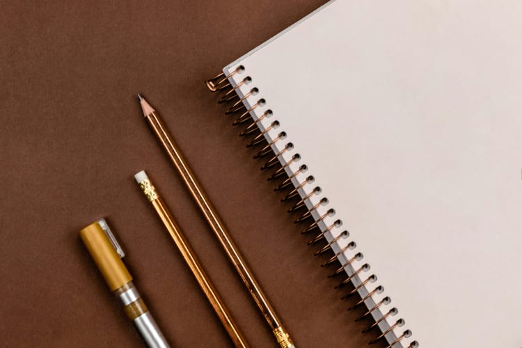 Bleistift, Collegeblock und Tintenroller liegen auf einem Tisch null