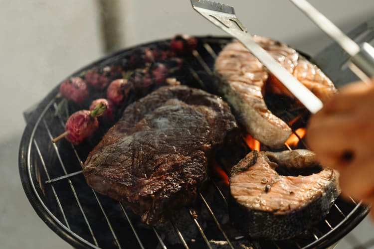 Ein Stück Fleisch und Lachssteaks auf einem Grill