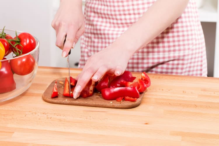 Rote Paprika auf einem Schneidebrett schneiden