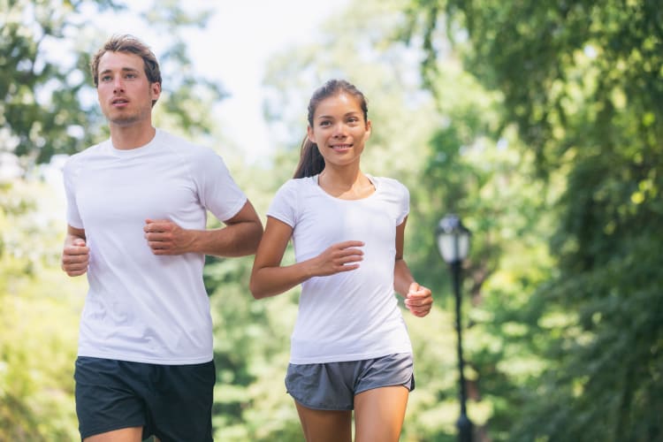 Läufer, die gemeinsam im Stadtpark trainieren und in weißen T-Shirts für einen guten Zweck laufen. Sport und Fitness: Freunde, die gemeinsam im Freien laufen.
