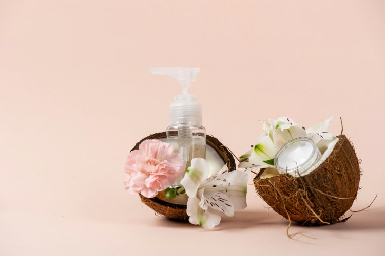 Kokoshälften in denen Blüten liegen und ein Fläschen Kokosöl null