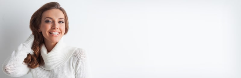 Porträt einer schönen jungen blonden Frau kaukasischer Herkunft mit makelloser Haut und perfektem Make-up in einem winterweißen Strickpullover