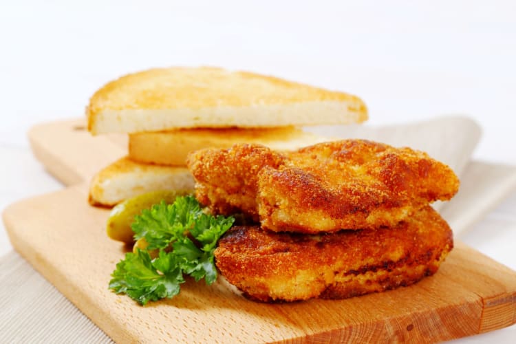 Goldbraun gebratene vegane Schnitzel mit frischer Petersilie und knusprigen Toastscheiben.