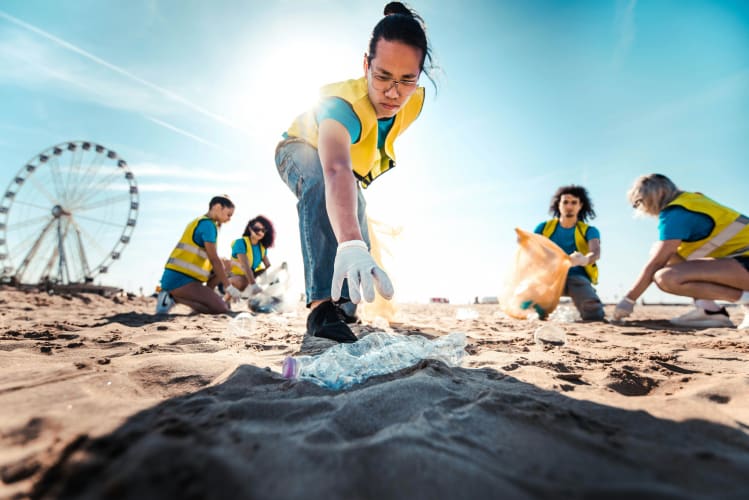 Frau sammelt Plastikflasche am Strand auf