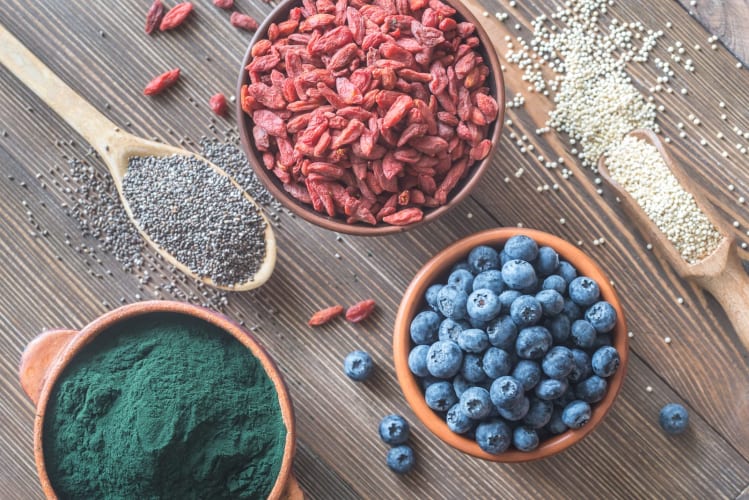 Schalen mit Superfoods auf Holzuntergrund: Draufsicht null