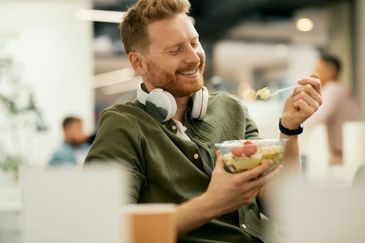 glucklicher-geschaftsmann-mit-einer-gesunden-mahlzeit-wahrend-der-mittagspause-bei-der-arbeit null