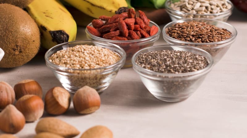Superfoods auf grauem Hintergrund mit Platz für Text. Nüsse, Bohnen, Blattgemüse und Samen. Gesunde vegane Ernährung. null