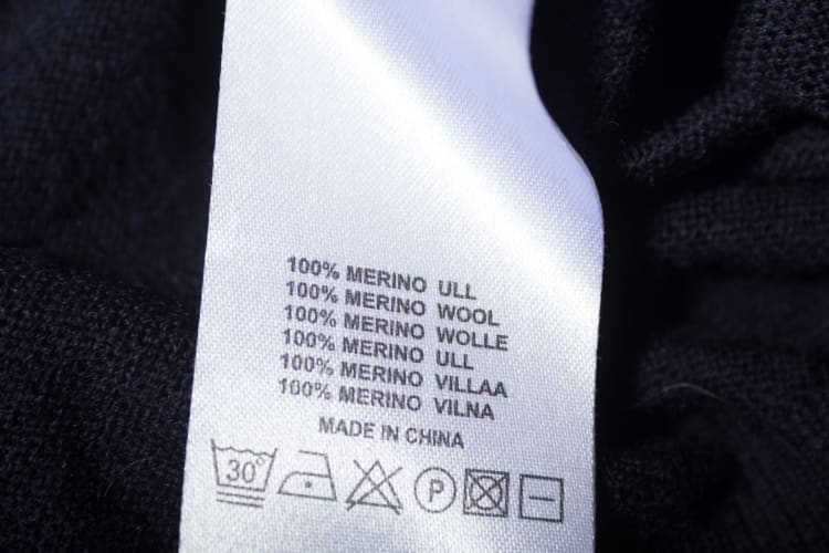 100-Merinowolle-Etikett auf dem dunkelblauen Wollstoff des Pullovers.