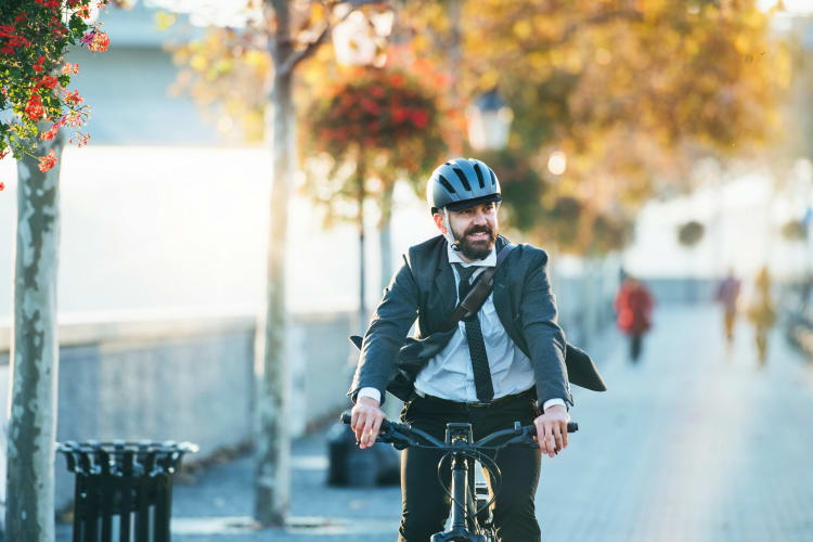 Geschäftsmann trägt Fahrradhelm und fährt mit einem E-Bike durch die Stadt  null