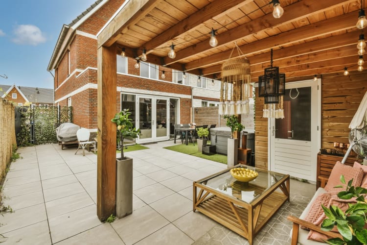 ein Außenwohnbereich mit Terrassenmöbeln und Topfpflanzen an der Seite des Hauses, umgeben von Backsteinmauern null