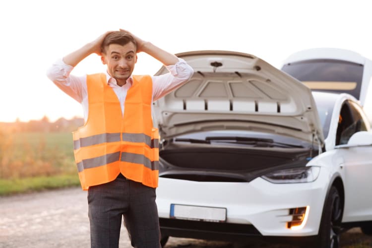 Mann in Warnweste vor Elektroauto